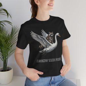Camiseta Las leyendas toman vuelo — Camiseta con estampado de mapache montando un cisne